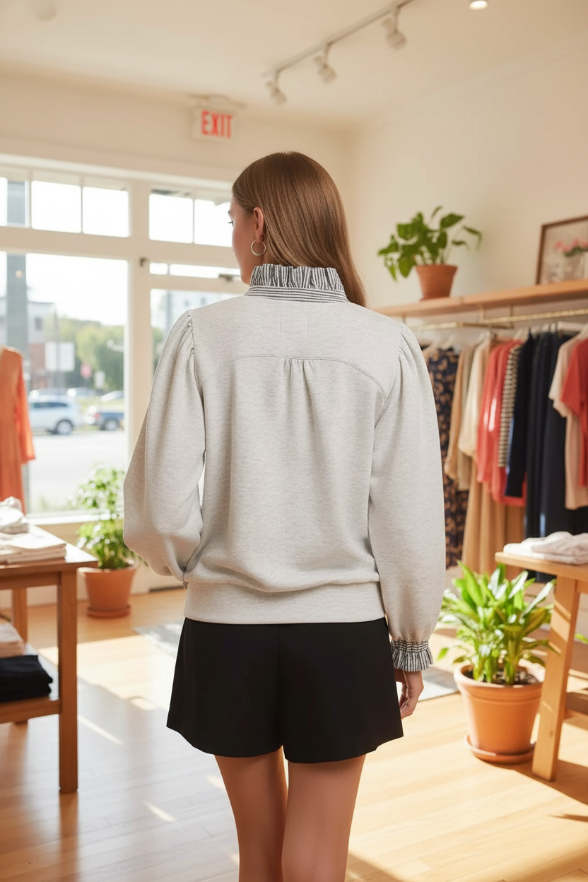 Back view of a blonde woman in the Umgee heather white french terry top with gathered back yoke, navy stripe ruffle collar, balloon puff sleeves with smocked ruffle cuffs, and ribbed hem, paired with black shorts