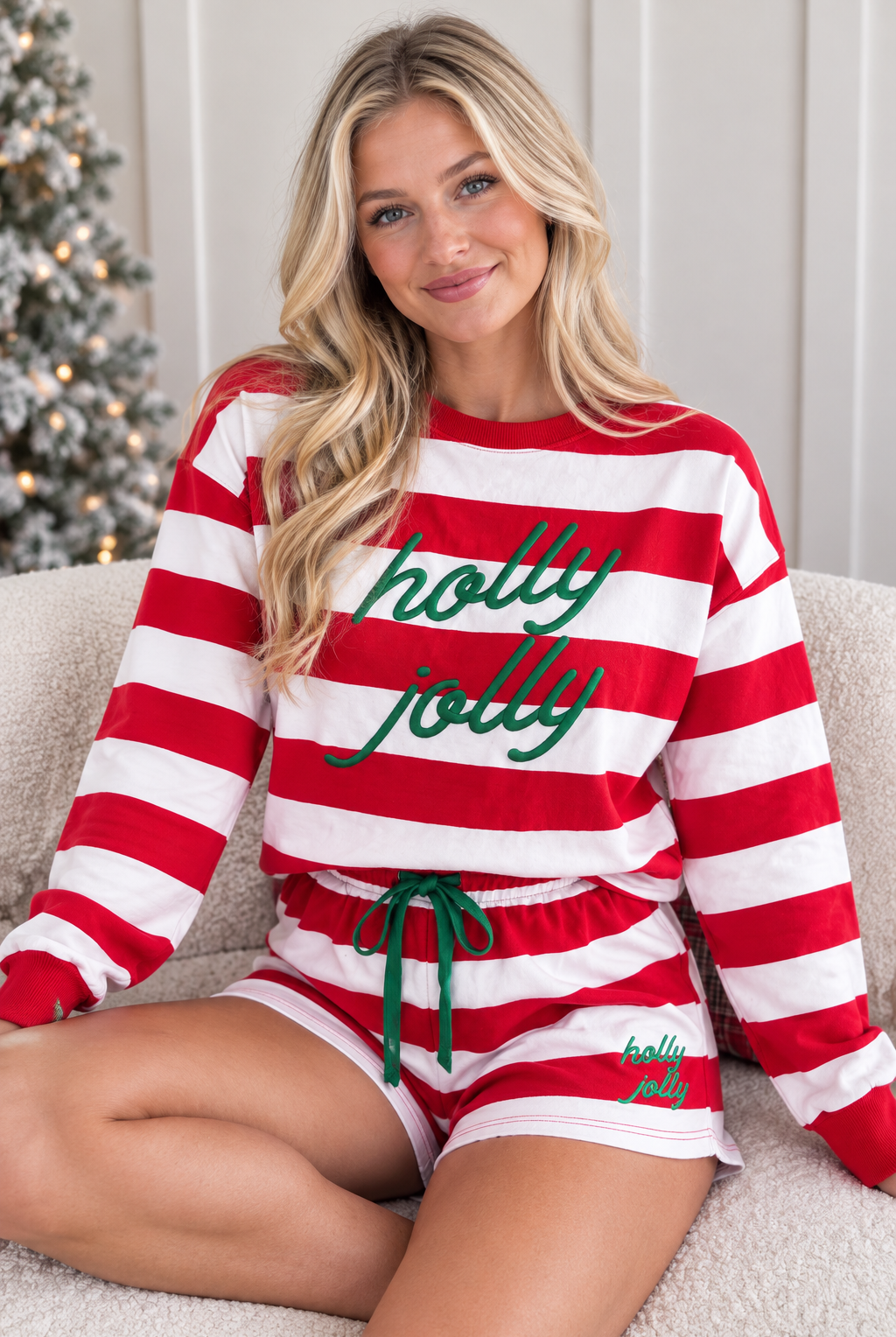Seated view of red stripe Holly Jolly embroidered pullover and matching shorts set