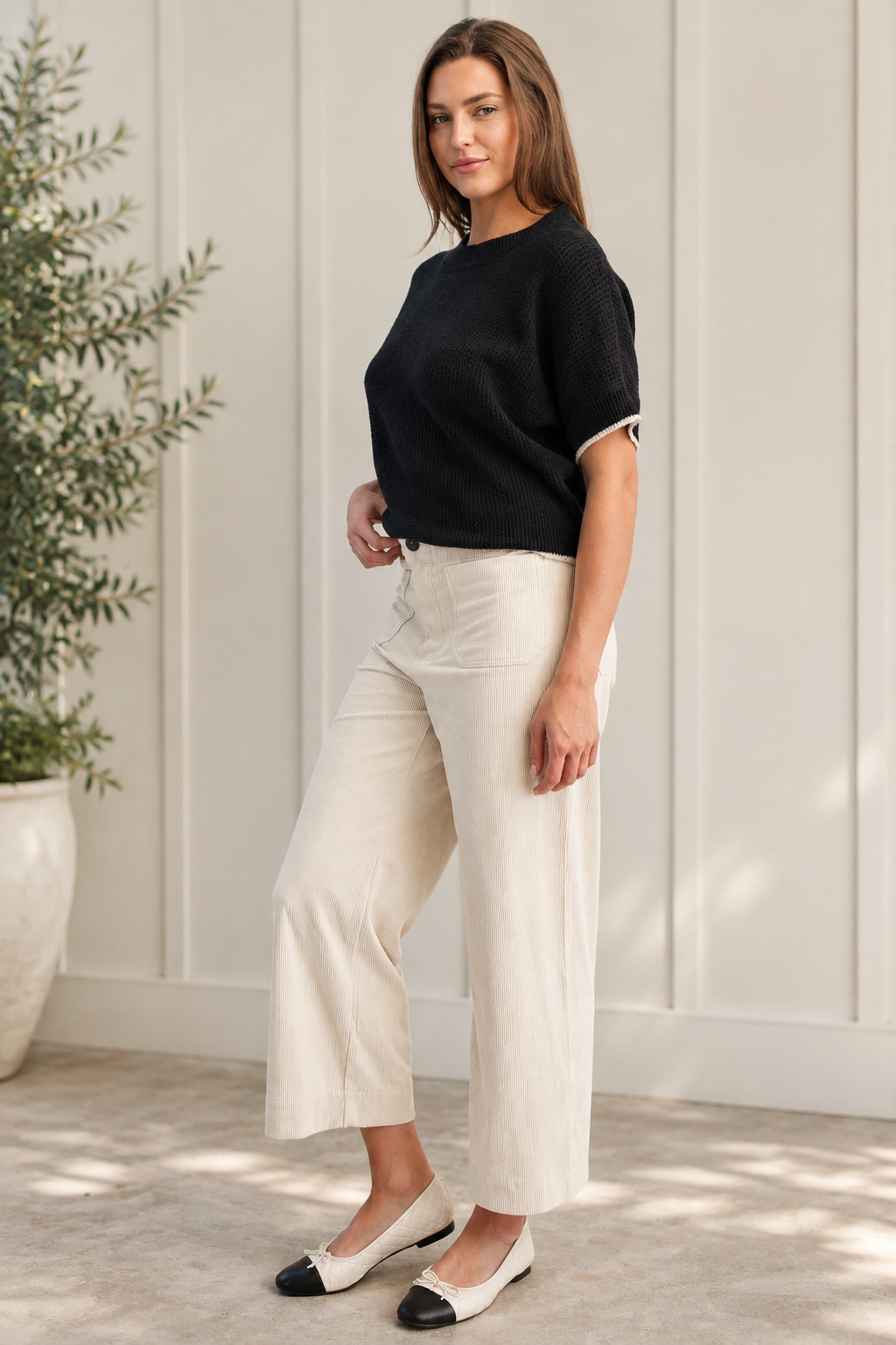 Angled view of beige corduroy pants with a cropped straight-leg silhouette and oversized front patch pockets.