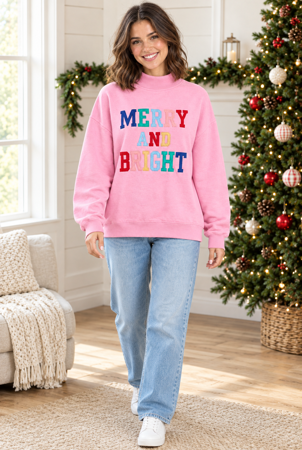 Full-length view of pink Merry and Bright mock neck pullover styled with light wash jeans and white sneakers