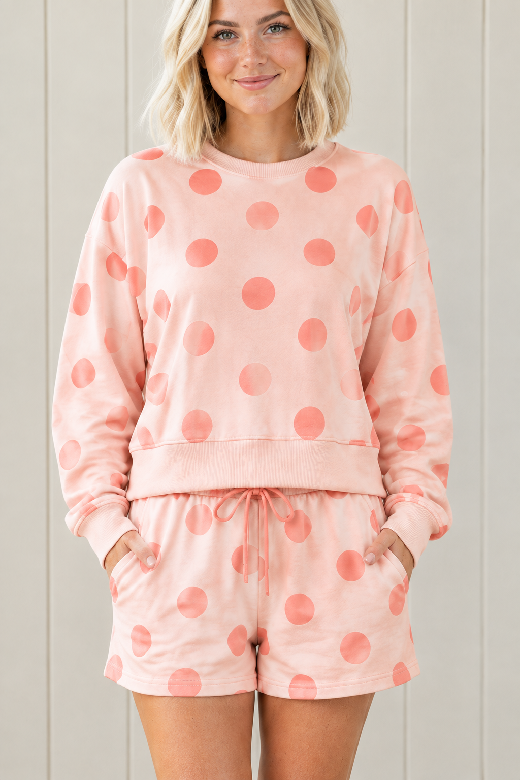 Close-up of pink lounge set with coral polka dots, solid pullover hem band and matching drawstring shorts