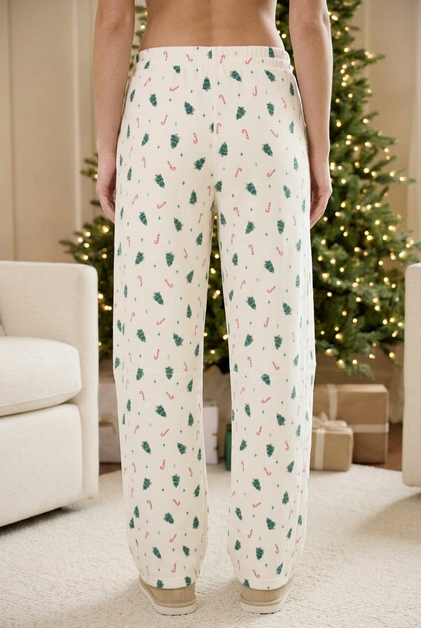 Back view of cream holiday sweatpants showing the elastic waistband, Christmas tree and candy cane print, and straight legs.