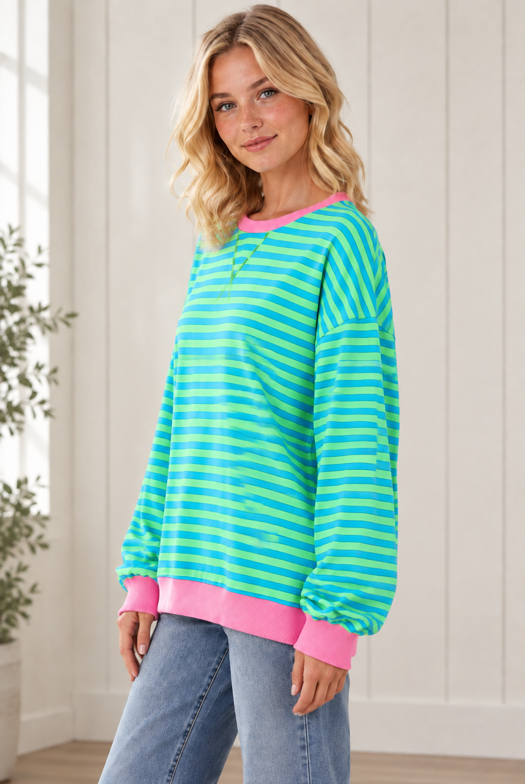 Side view of relaxed striped pullover showing dropped shoulders, loose sleeves and pink contrast trim.
