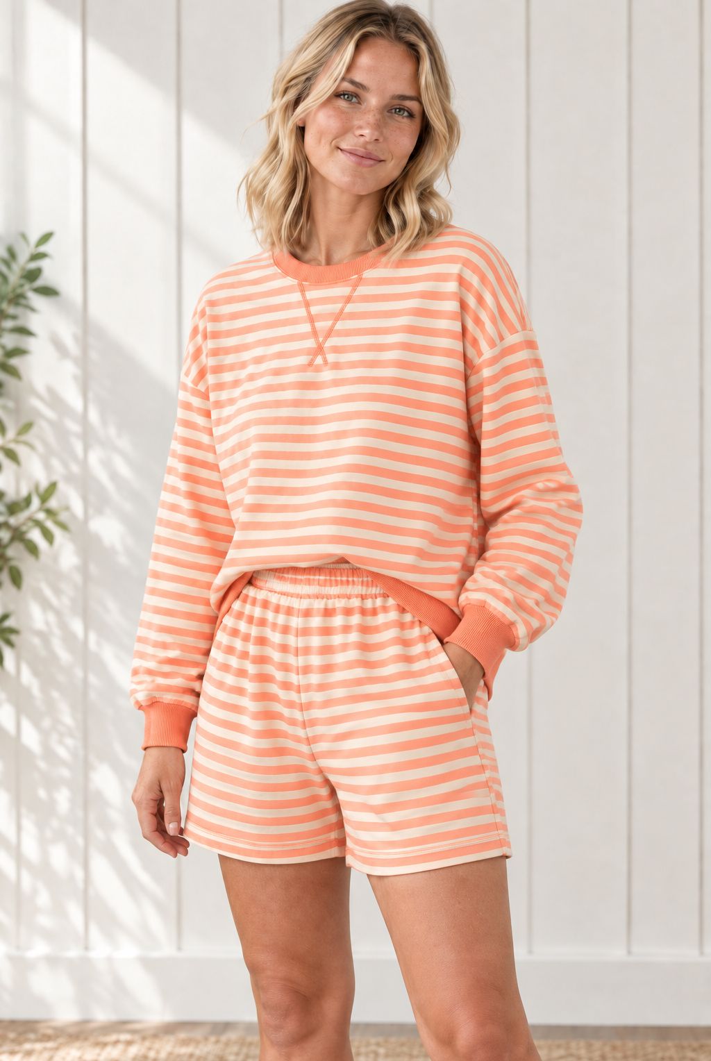 Angled front view of orange and cream striped pullover and shorts set with dropped shoulders and side pockets