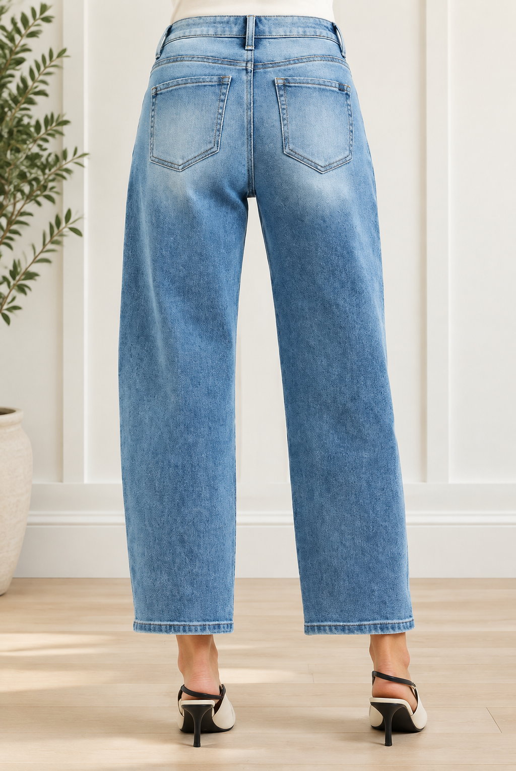 Back view of medium wash barrel jeans highlighting back pockets, yoke stitching and cropped hems
