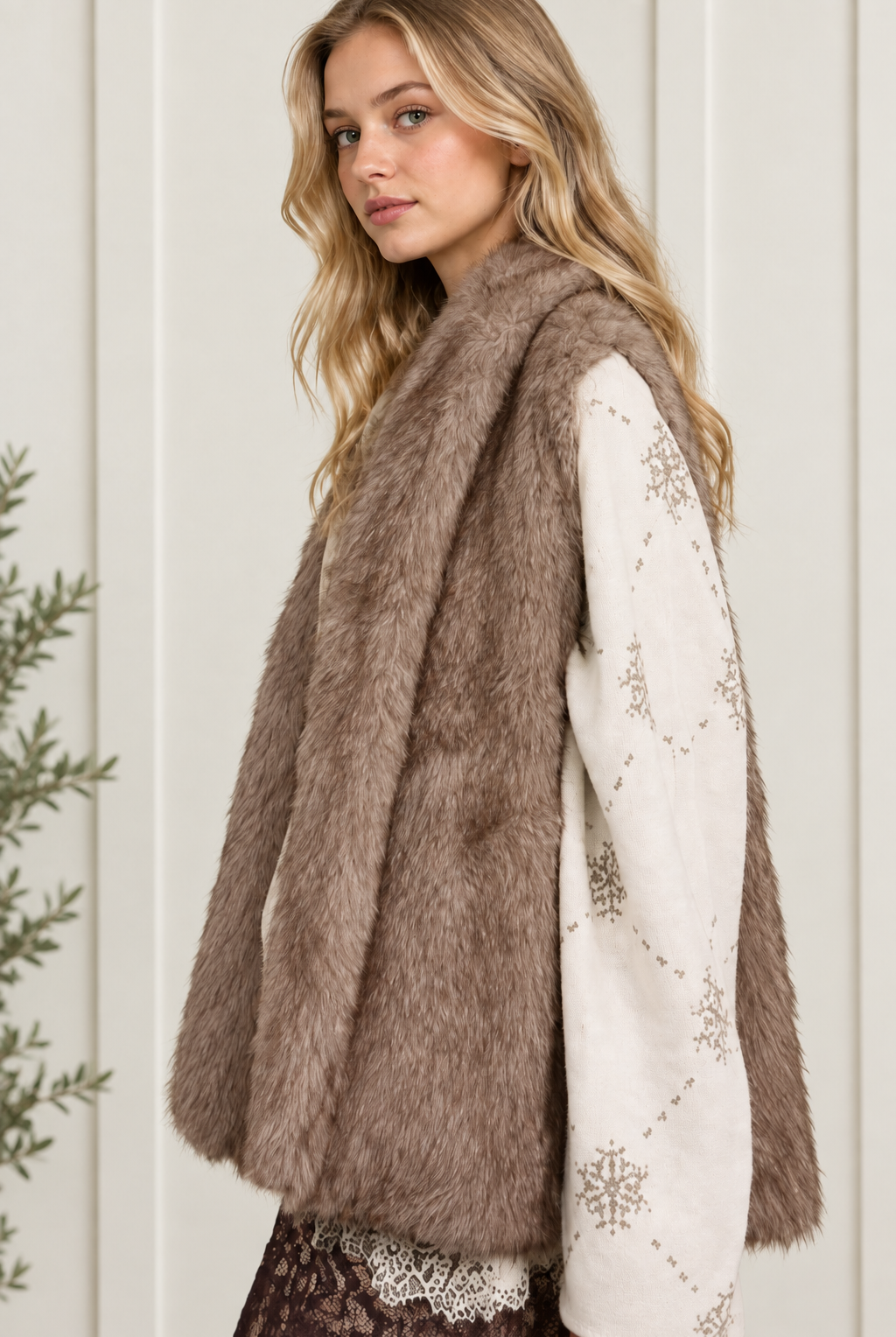 Side view of taupe faux fur shawl vest showing its sleeveless cut and layering silhouette