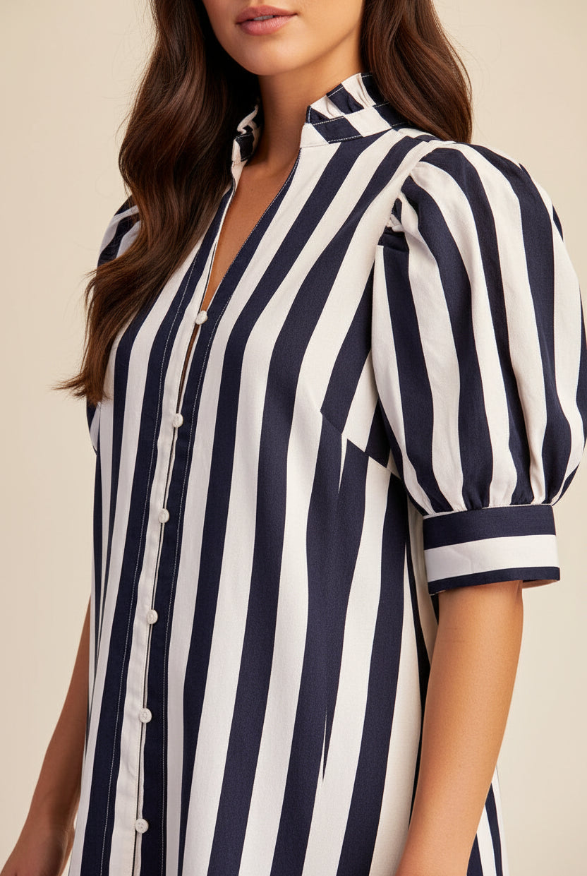 A close-up of a woman wearing a navy and white vertically striped dress with puff sleeves and a button-front collar.