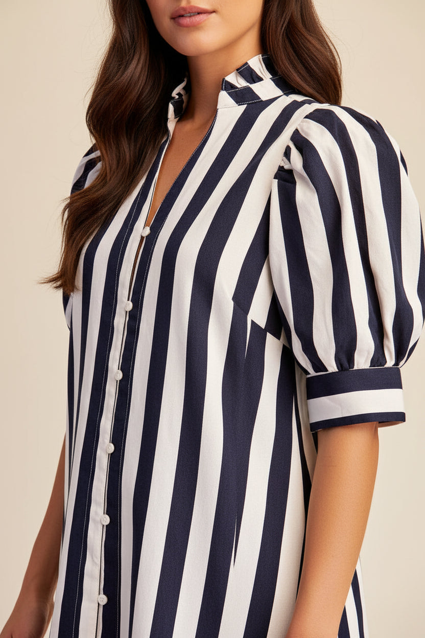A close-up of a woman wearing a navy and white vertically striped dress with puff sleeves and a button-front collar.