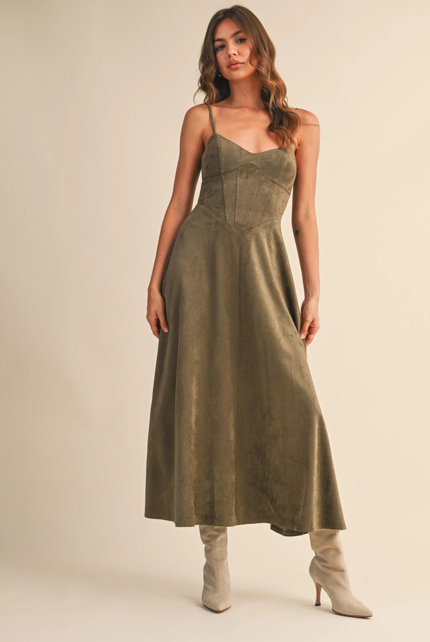Woman wearing an olive suede bustier midi dress with adjustable straps and a flared skirt — trendy boutique fall outfit.