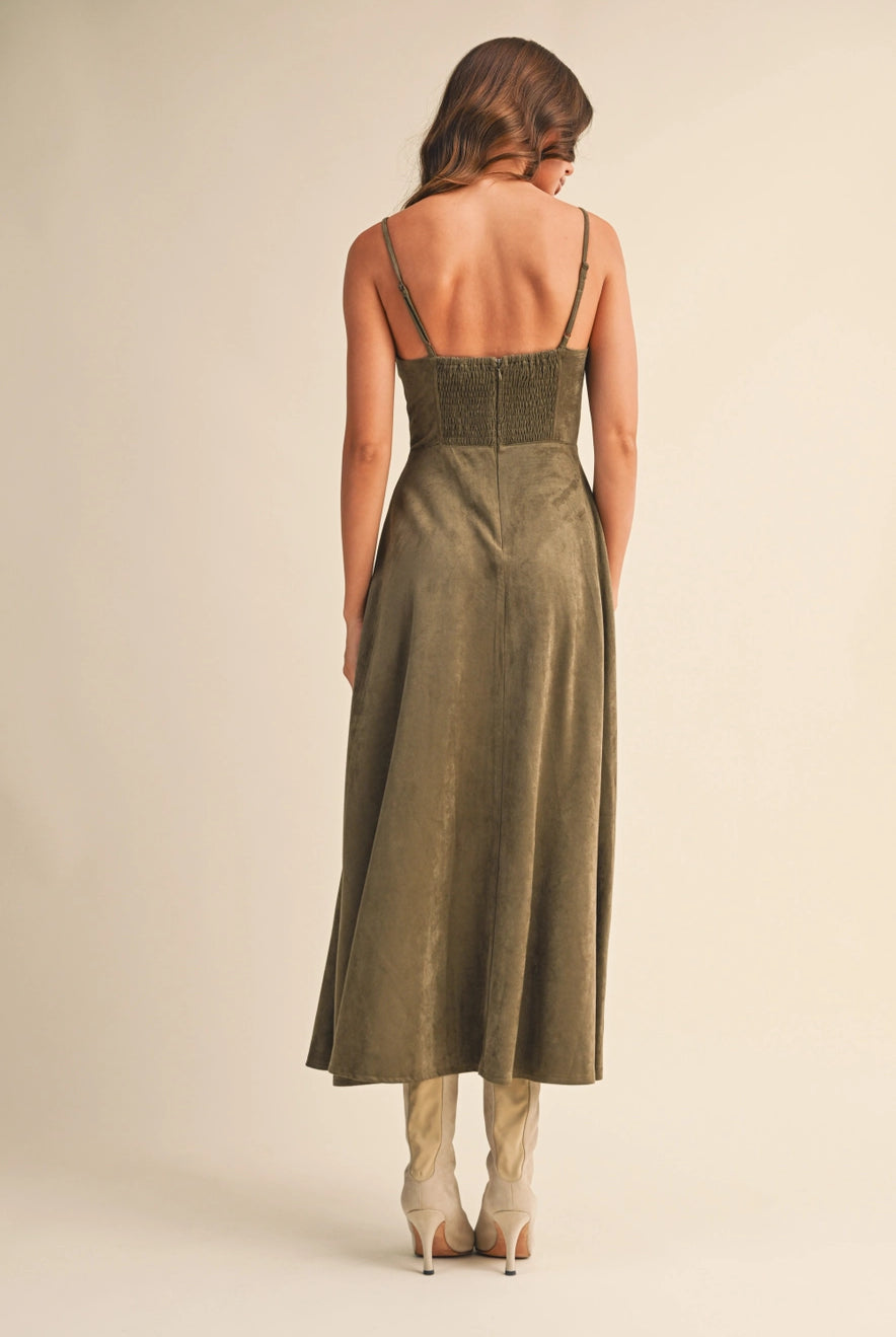 Woman wearing an olive suede bustier midi dress with adjustable straps and a flared skirt — trendy boutique fall outfit.