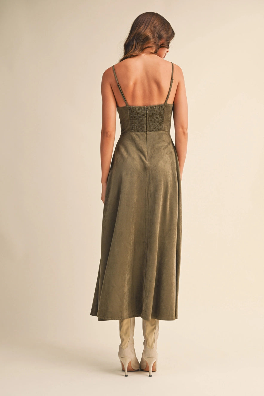 Woman wearing an olive suede bustier midi dress with adjustable straps and a flared skirt — trendy boutique fall outfit.