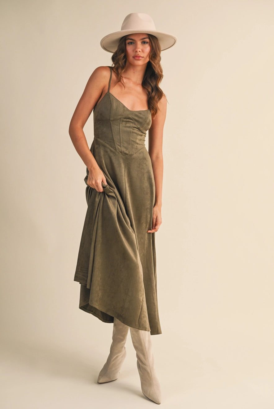 Woman wearing an olive suede bustier midi dress with adjustable straps and a flared skirt — trendy boutique fall outfit.