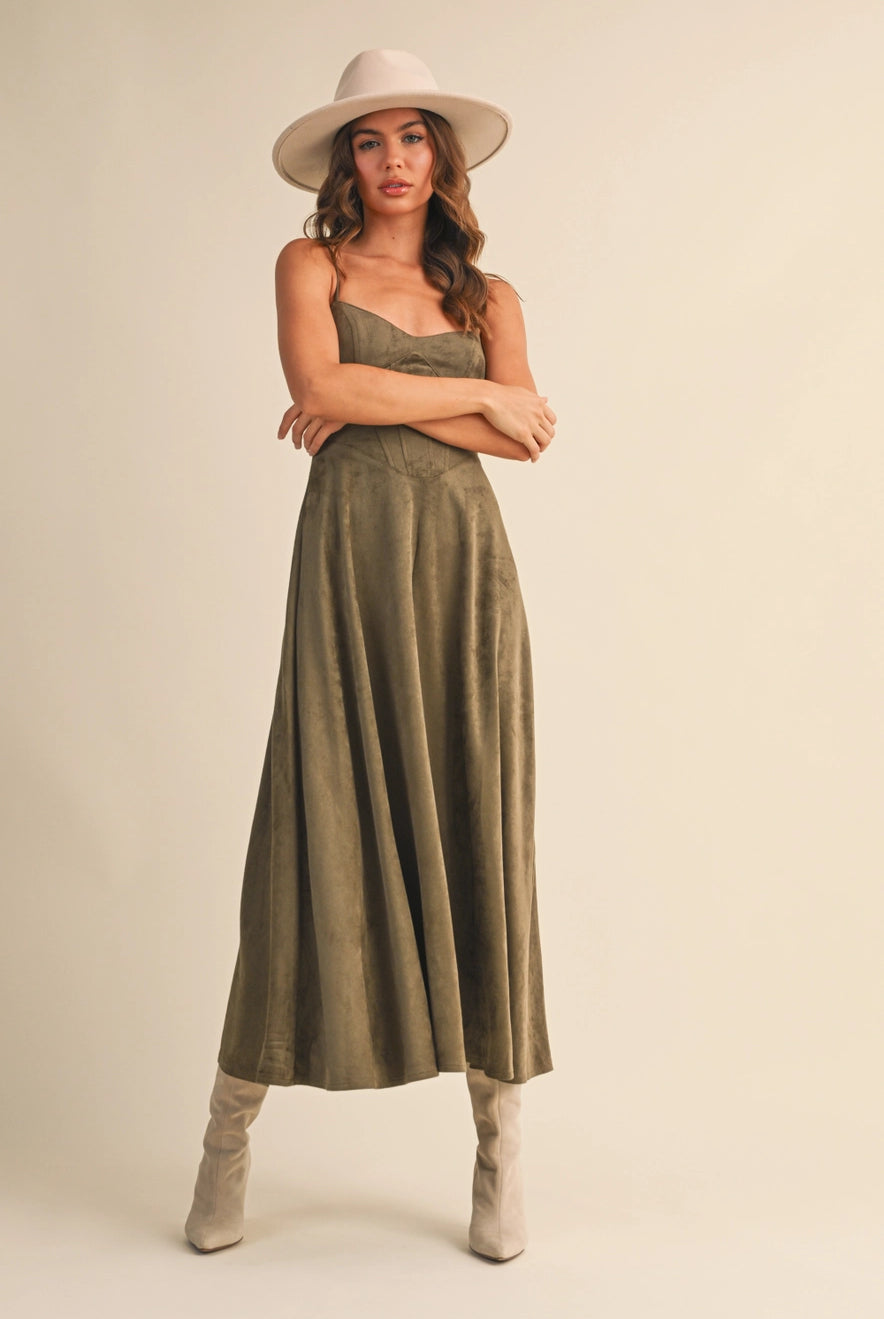 Woman wearing an olive suede bustier midi dress with adjustable straps and a flared skirt — trendy boutique fall outfit.