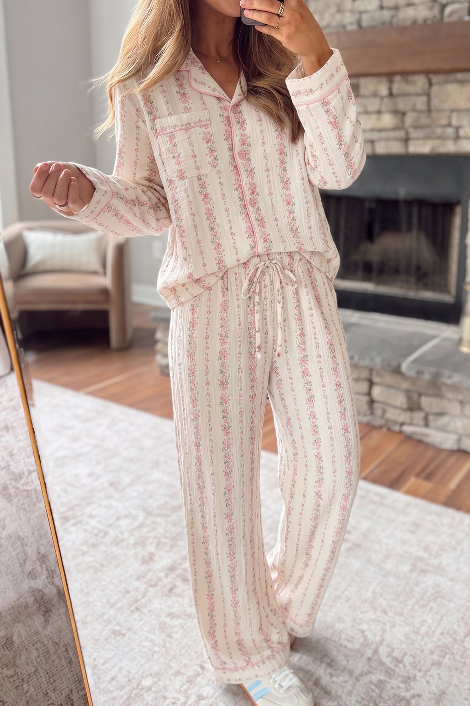 A woman wearing a matching long-sleeve pajama set with a cream base and pink floral vertical stripes