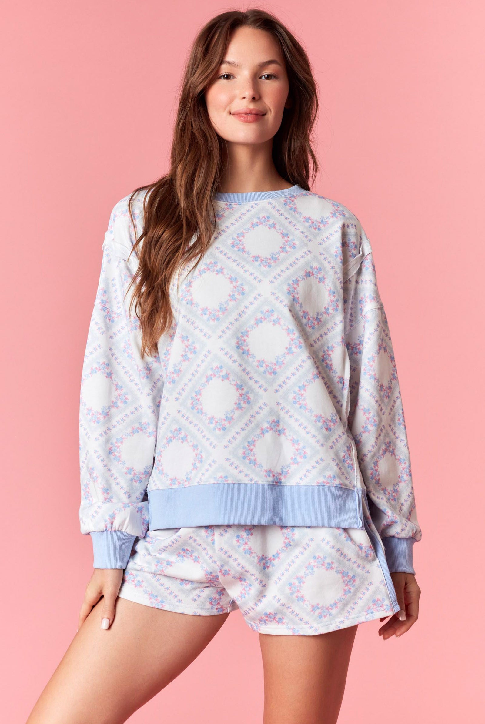 Woman wearing a pink and blue pastel floral printed French terry sweatshirt with ribbed trim, part of a matching lounge set
