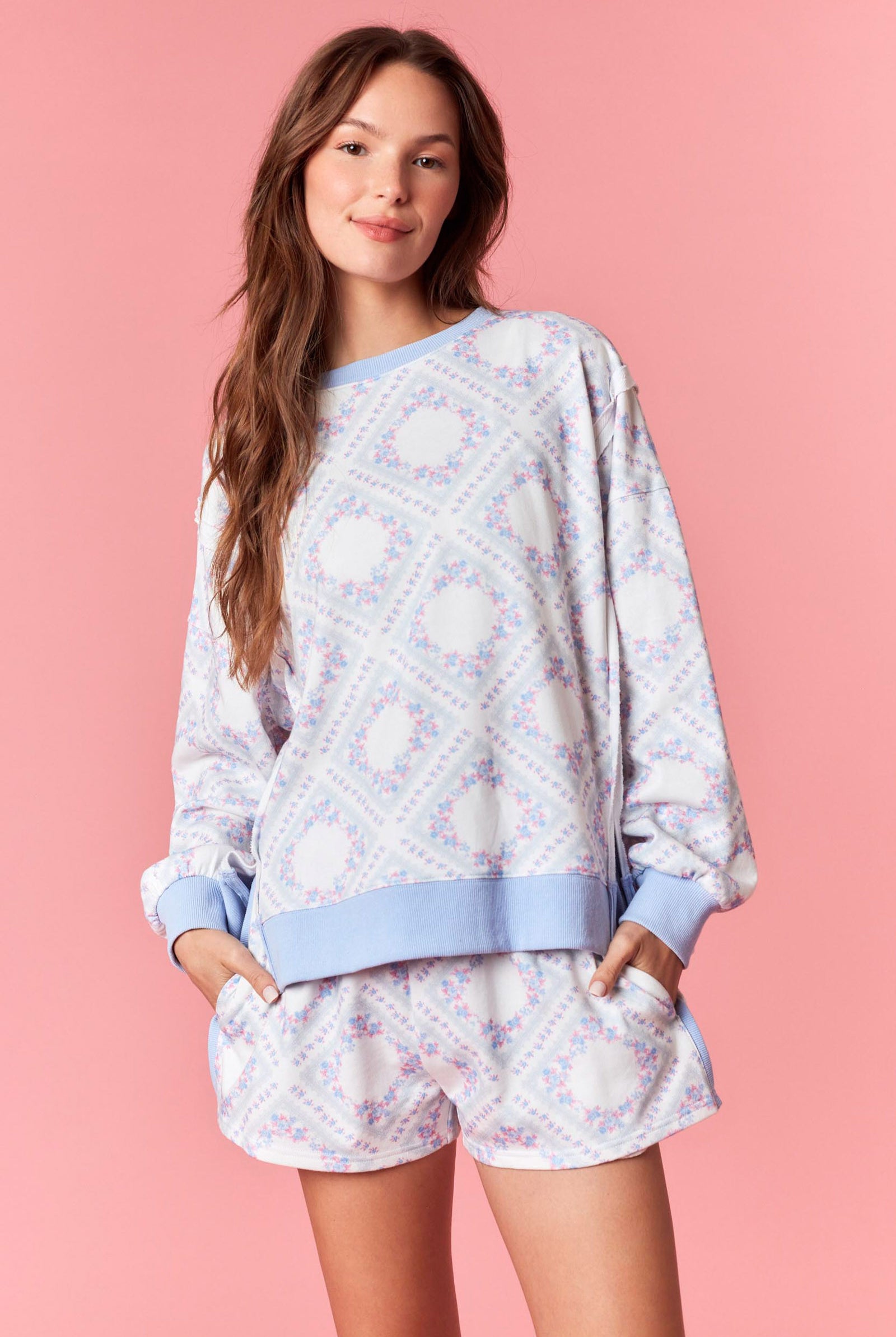 Woman wearing a pink and blue pastel floral printed French terry sweatshirt with ribbed trim, part of a matching lounge set