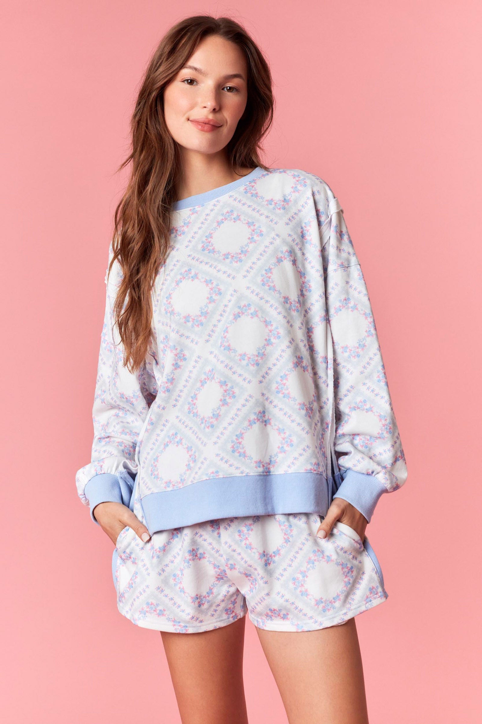 Woman wearing a pink and blue pastel floral printed French terry sweatshirt with ribbed trim, part of a matching lounge set