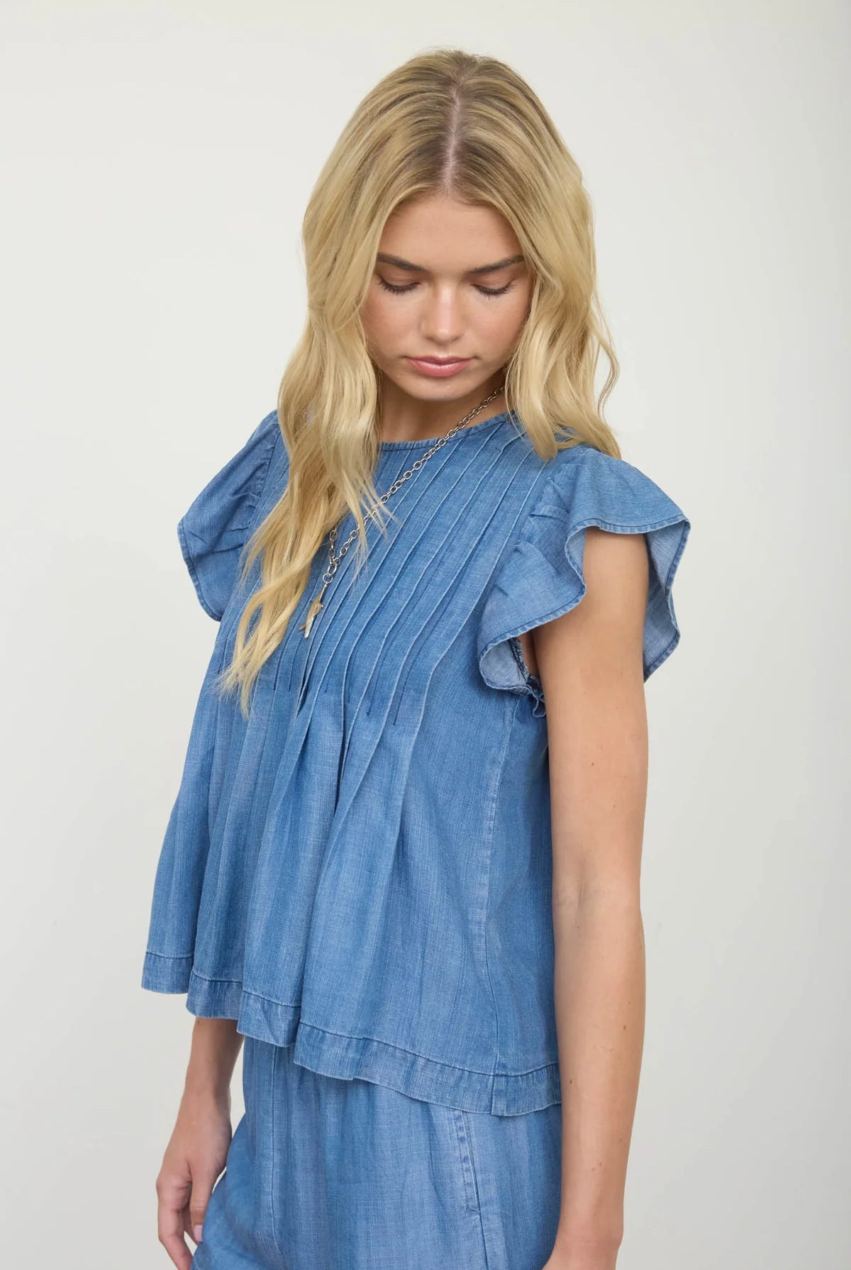 Side profile of ruffle sleeve denim top showing relaxed fit and ruffle hem