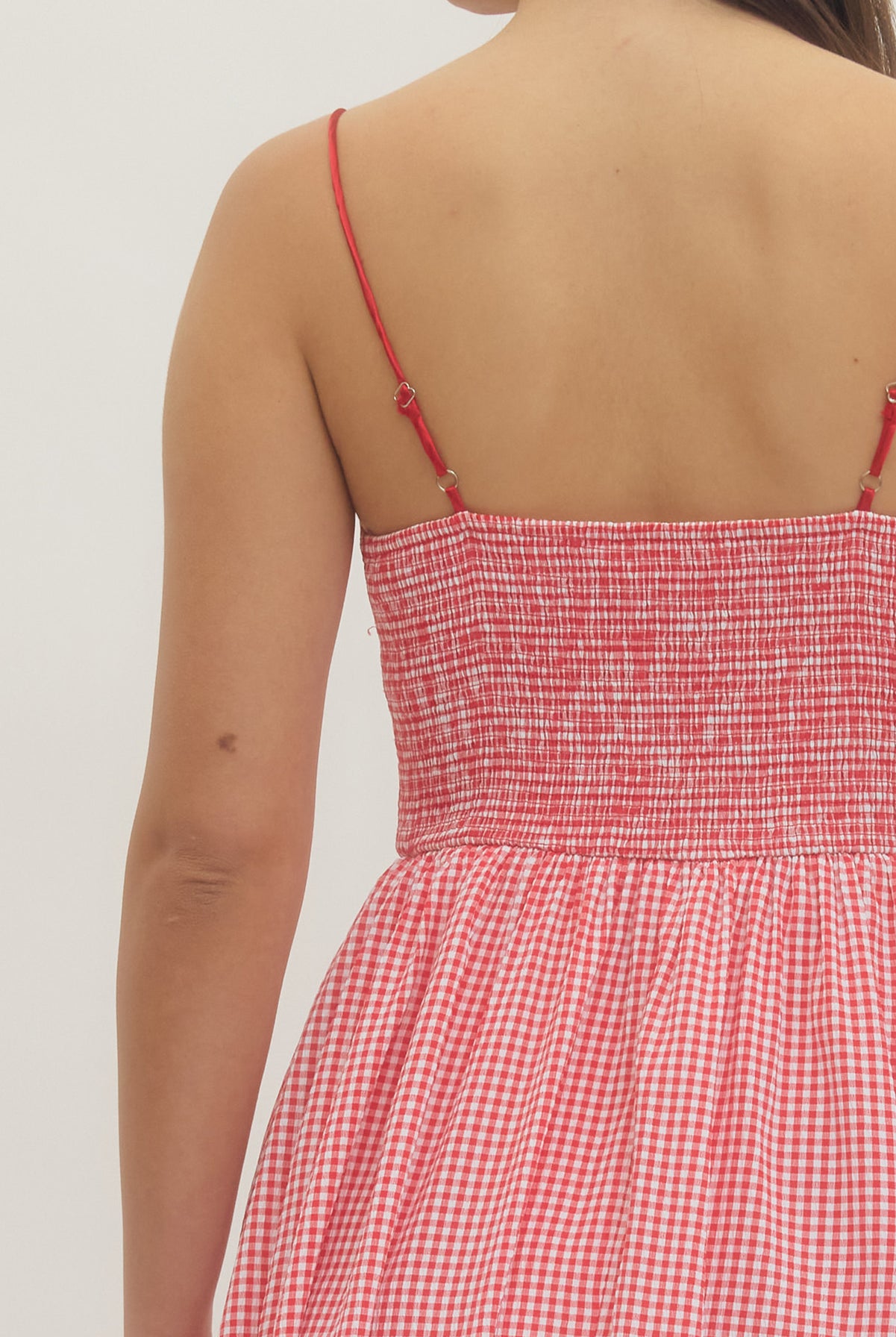 Model wearing a sweetheart gingham maxi dress with adjustable straps, bow details, smocked back, and side pockets in a romantic gingham print, perfect for Valentine’s Day and spring occasions.