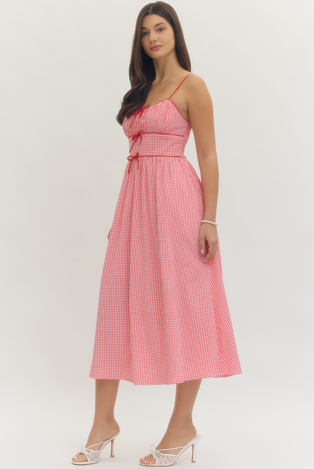 Model wearing a sweetheart gingham maxi dress with adjustable straps, bow details, smocked back, and side pockets in a romantic gingham print, perfect for Valentine’s Day and spring occasions.