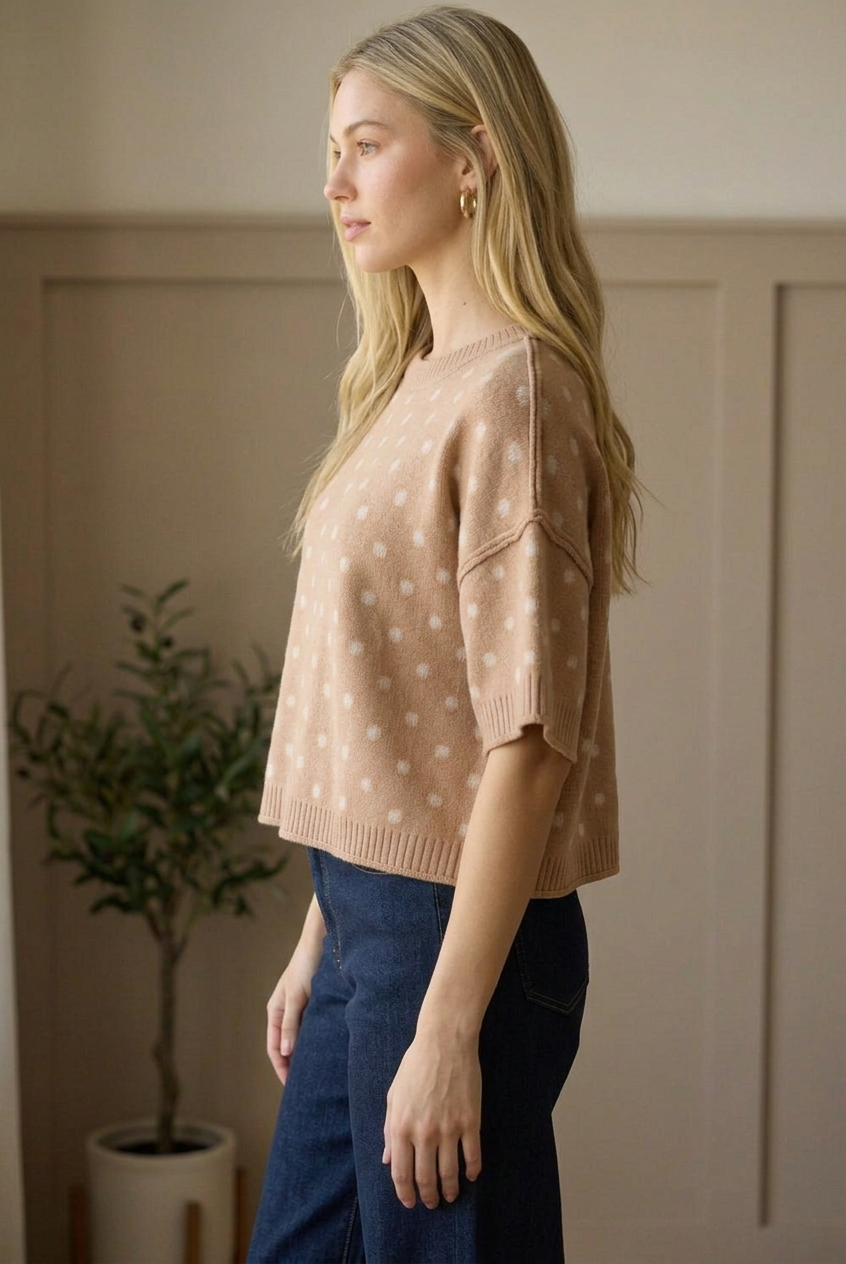 Side profile of a camel polka dot short sleeve sweater top showing its relaxed boxy silhouette and ribbed hem