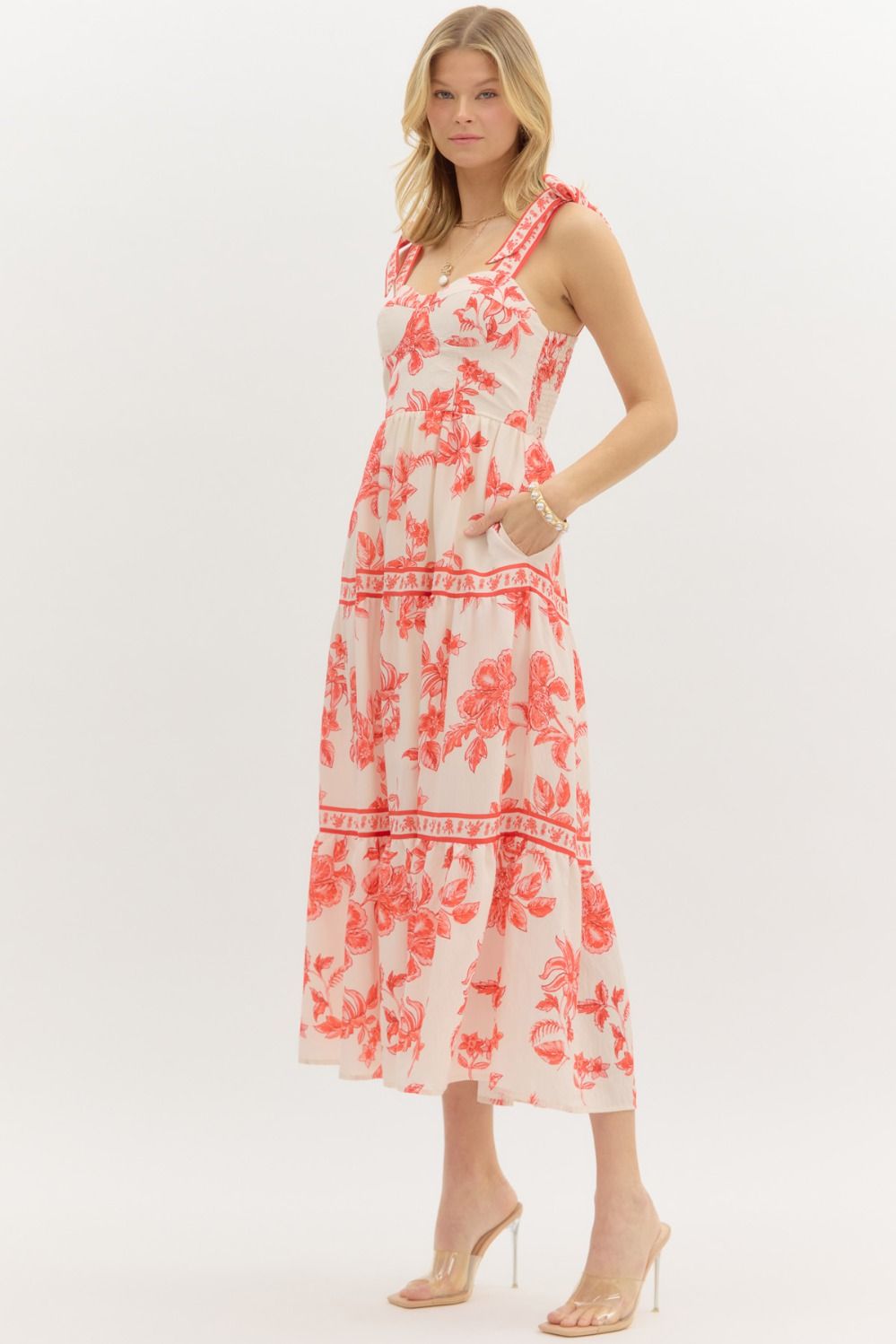 Model wearing a cream and burnt orange floral tiered maxi dress with tie straps, lined with hidden side pockets – Sunset Soirée Maxi