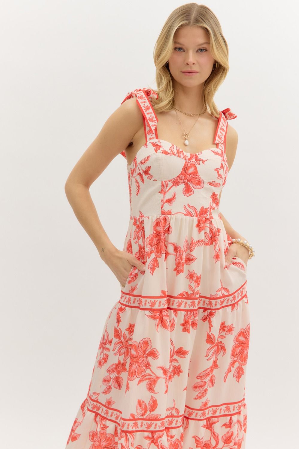 Model wearing a cream and burnt orange floral tiered maxi dress with tie straps, lined with hidden side pockets – Sunset Soirée Maxi