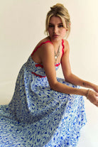 Woman wearing a patriotic-themed maxi dress with a blue and white heart pattern, red scalloped trim, and smocked bodice