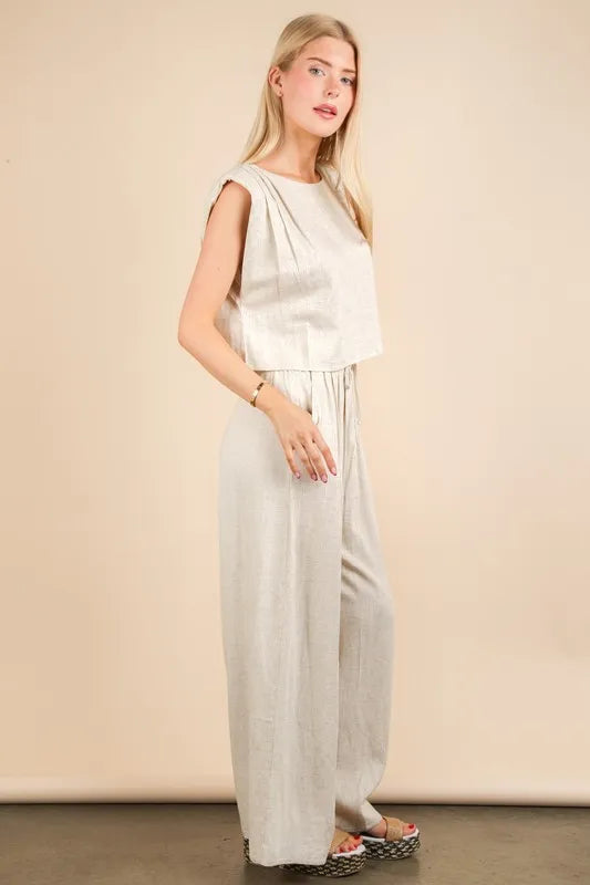  woman wearing a beige woven two-piece set with wide-leg pants and a sleeveless cropped top, styled for a chic minimalist look
