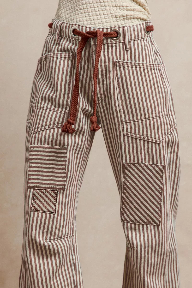 Close-up detail of striped barrel pants showing drawstring waist with rope tie and multiple cargo pockets with directional stripe placement
