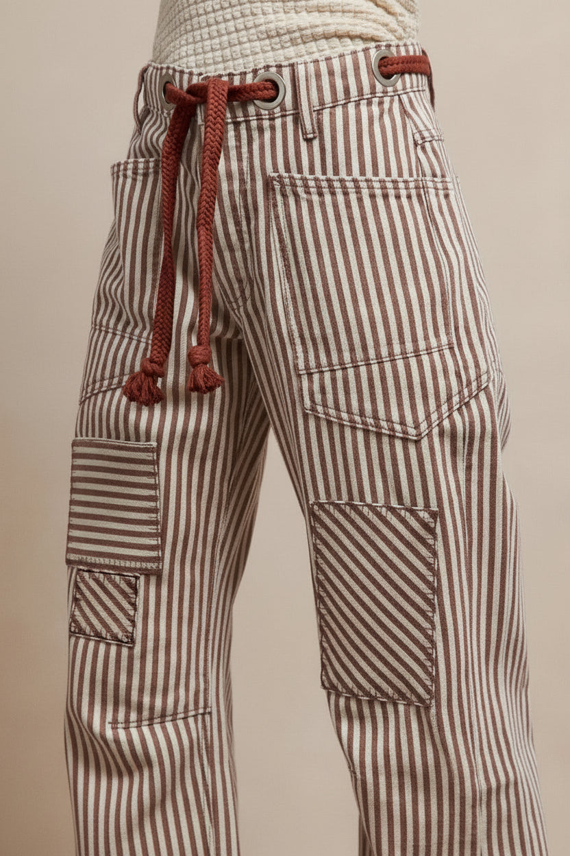 Close-up detail of striped barrel pants showing drawstring waist with rope tie and multiple cargo pockets with directional stripe placement