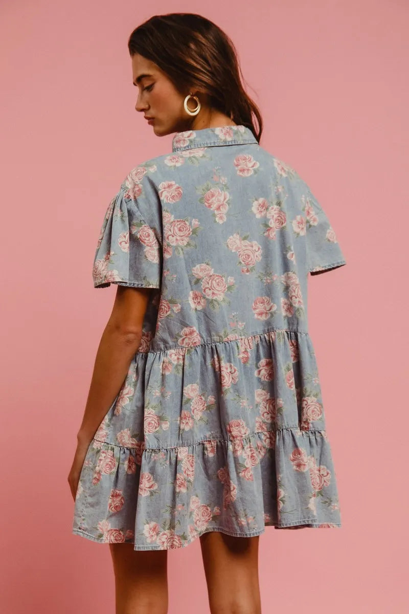 Model wearing the Wild Rose Shirt Dress in soft blue with rose print, flutter sleeves, and tiered ruffle skirt
