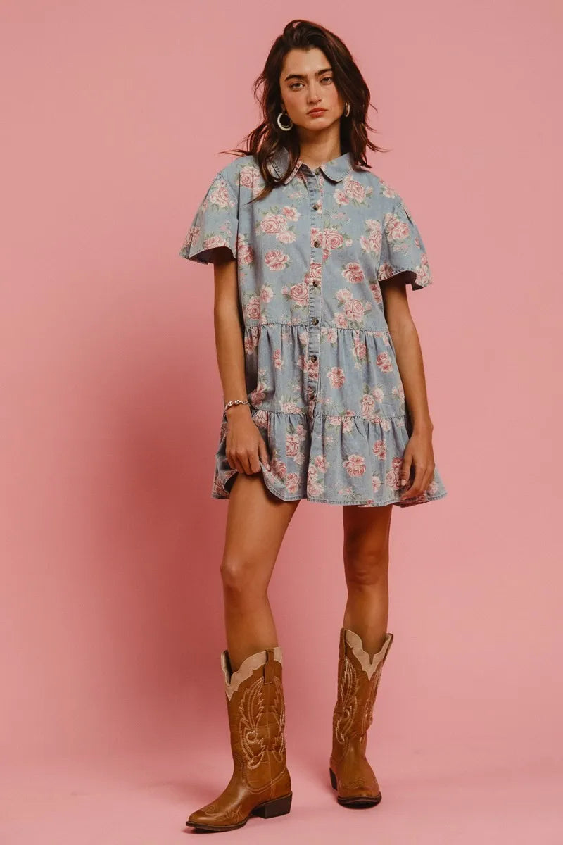 Model wearing the Wild Rose Shirt Dress in soft blue with rose print, flutter sleeves, and tiered ruffle skirt