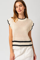 Model wearing a sleeveless round neck crop top with ruffle sleeves and color contrast trim, styled with high-waisted jeans — perfect for casual summer outings or brunch dates.