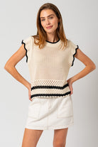 Model wearing a sleeveless round neck crop top with ruffle sleeves and color contrast trim, styled with high-waisted jeans — perfect for casual summer outings or brunch dates.