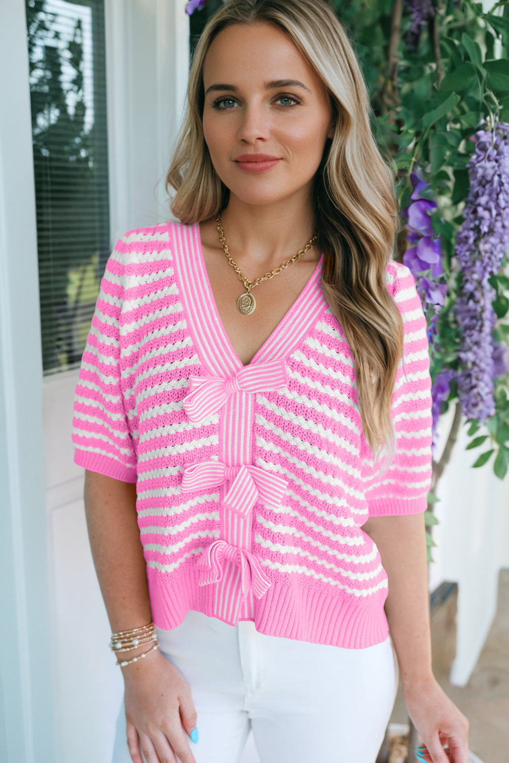 Woman wearing a pink and white striped sweater with a blurred outdoor background