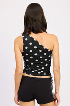 Black one-shoulder top with white polka dots worn by a person on a plain background rear view