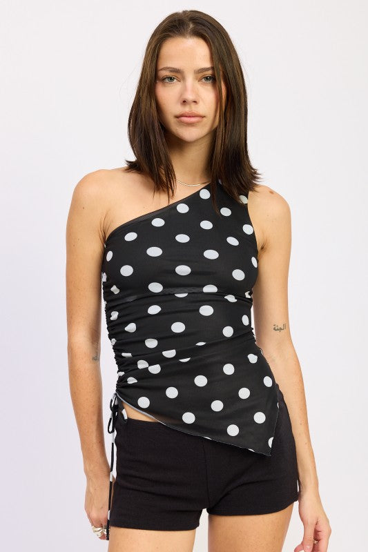 Black one-shoulder top with white polka dots worn by a person on a plain background asymmetrical tie side 