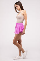 Woman wearing a pink ruffle hem tennis skirt with hidden inner pockets, styled for activewear and summer fashion.