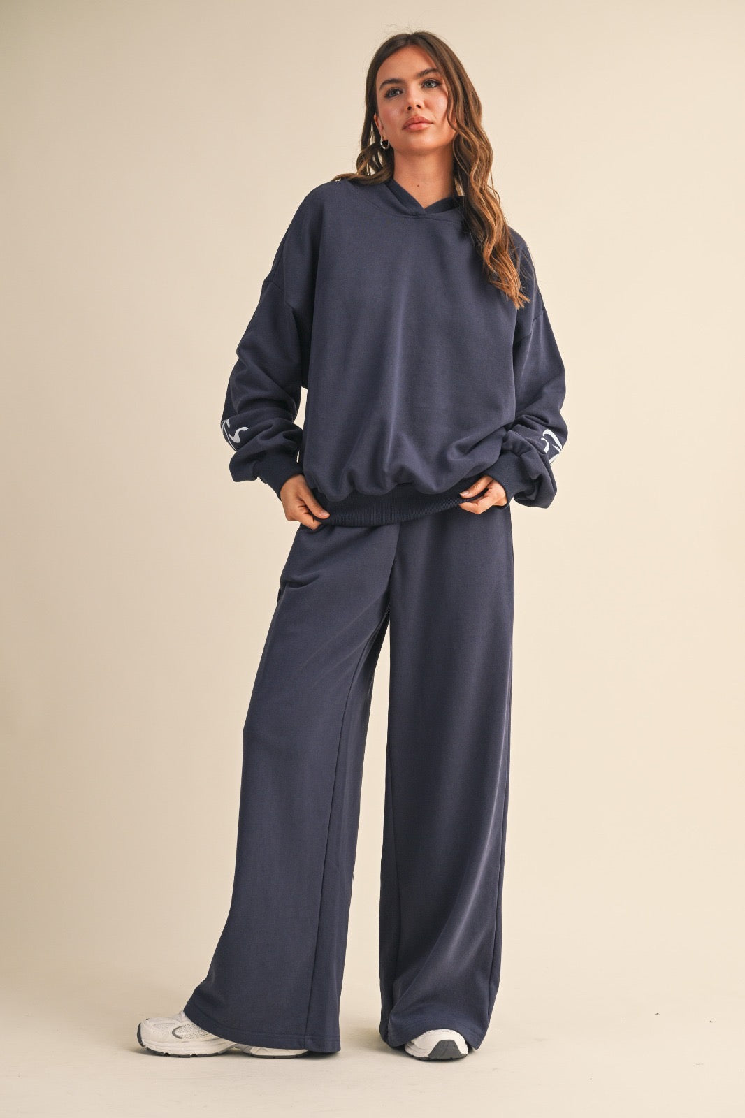 Model wearing navy wide-leg sweatpants with light blue bow details, styled with a matching navy hoodie.