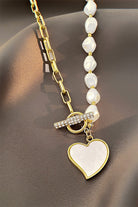 Necklace with heart pendant and beaded chain on a brown surface