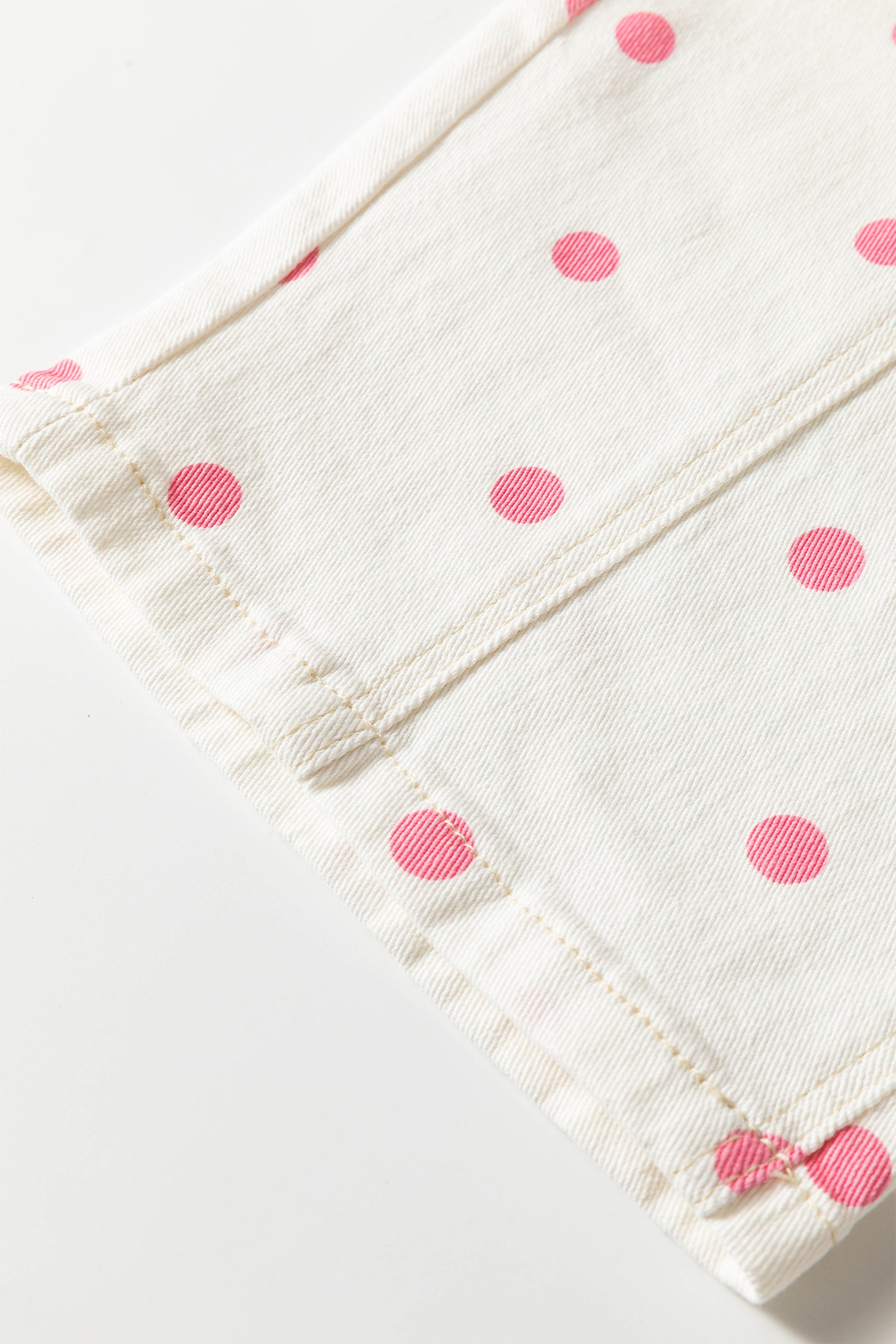 White fabric with pink polka dots on a white background
