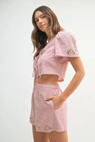 Two-piece outfit featuring a crochet lace crop top and matching high-waisted shorts, styled for a soft and feminine summer look.

