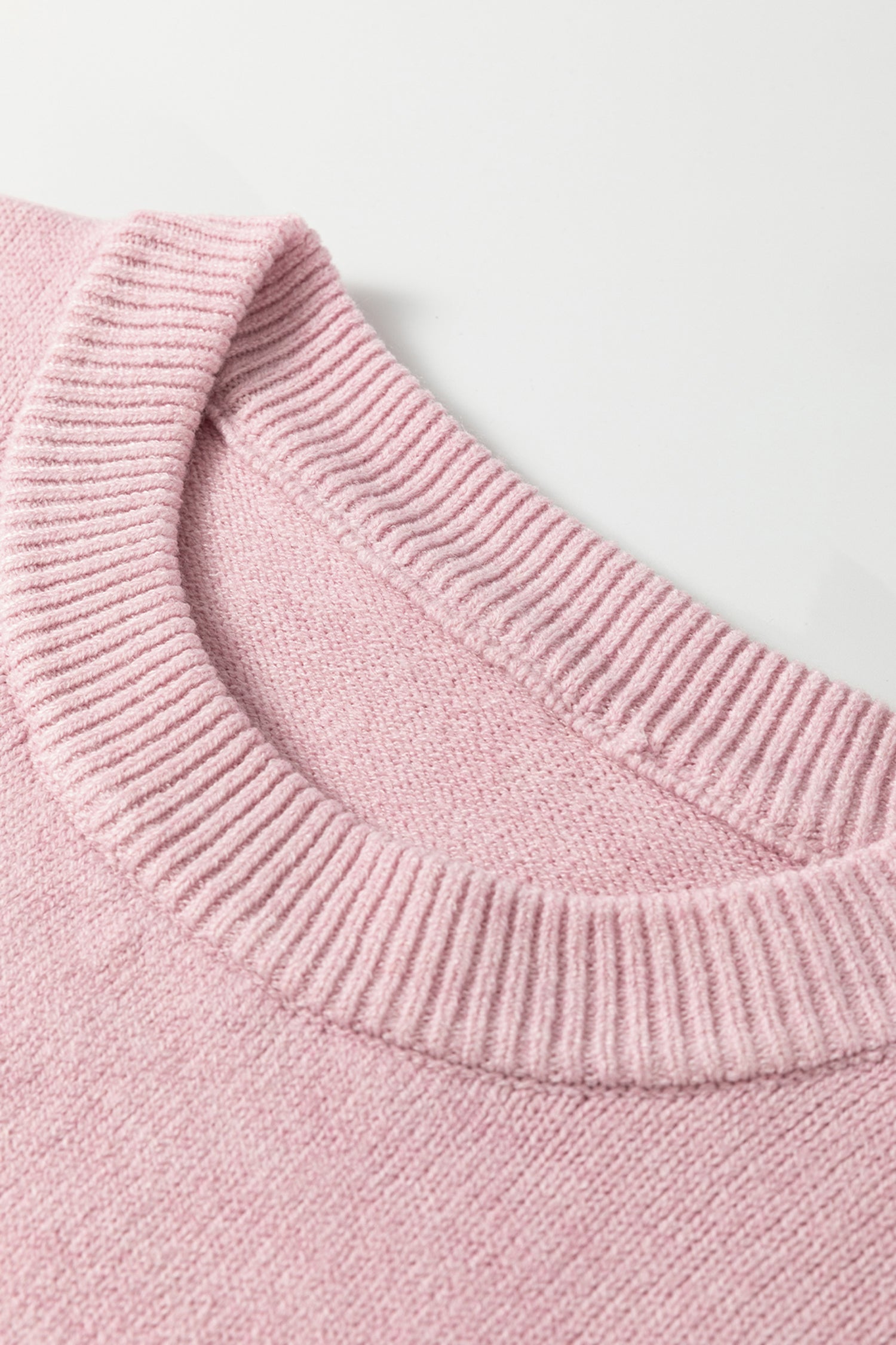 Close-up of a pink knitted sweater collar on a light background
