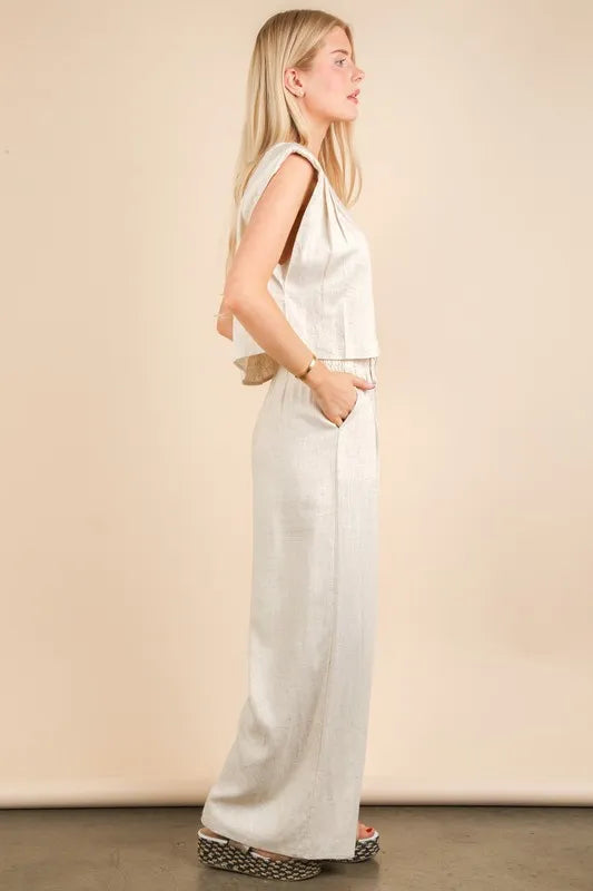  woman wearing a beige woven two-piece set with wide-leg pants and a sleeveless cropped top, styled for a chic minimalist look