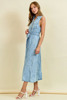 Sleeveless light wash denim midi dress with button front, tie waist belt, and ruffle hem