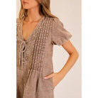 Casual washed utility romper featuring a deep V neck, adjustable-looking front tie detail, short sleeves, and relaxed shorts from Thread Bar Boutique