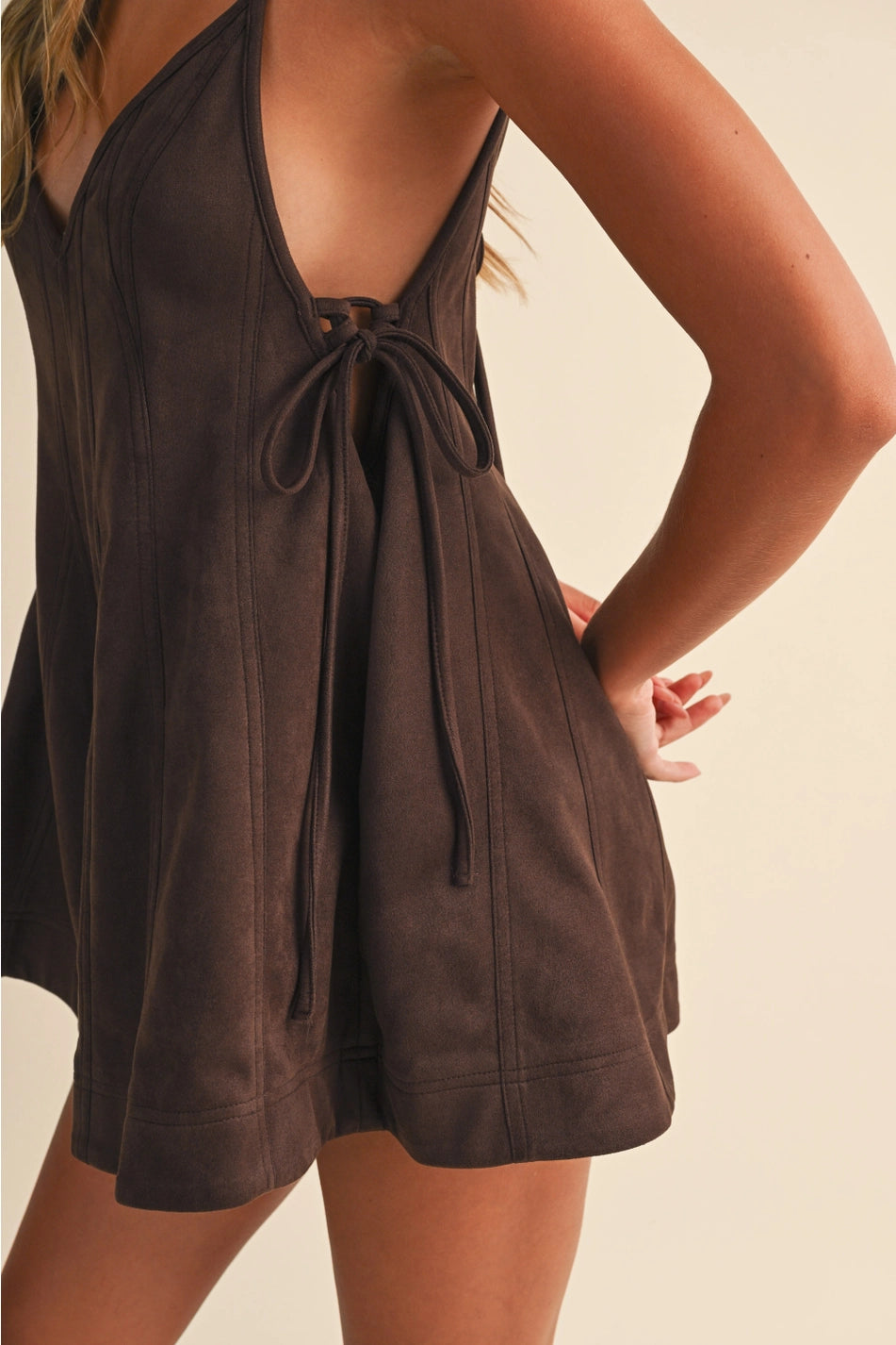 Close up Chocolate Brown Flare Chocolate brown textured flare romper with V-neckline, spaghetti straps, tie-side waist, and short flared hem
