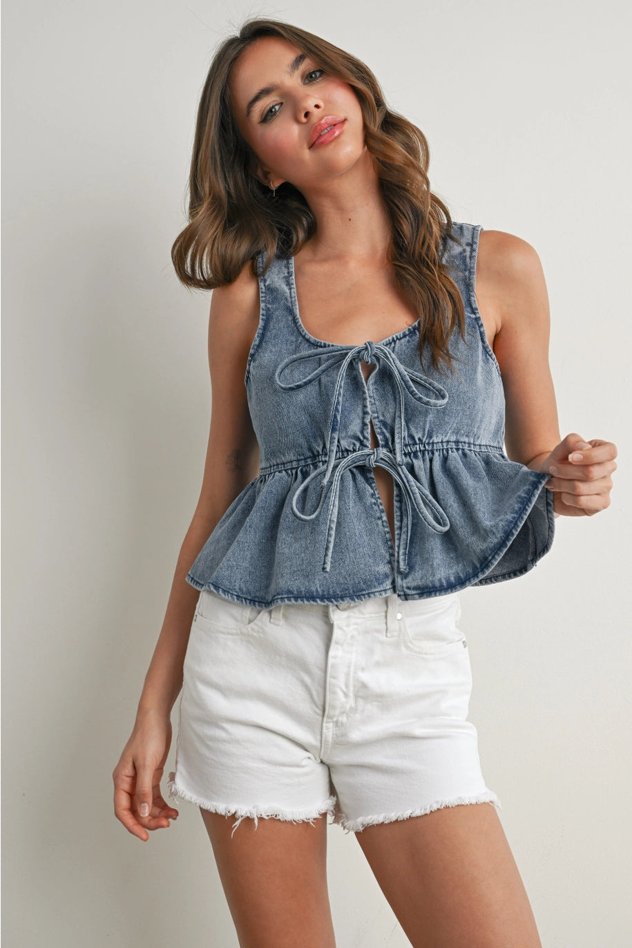 Woman wearing a denim peplum top and white shorts on a plain background