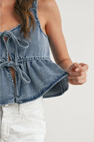 Denim top with ruffled details worn by a person on a plain background